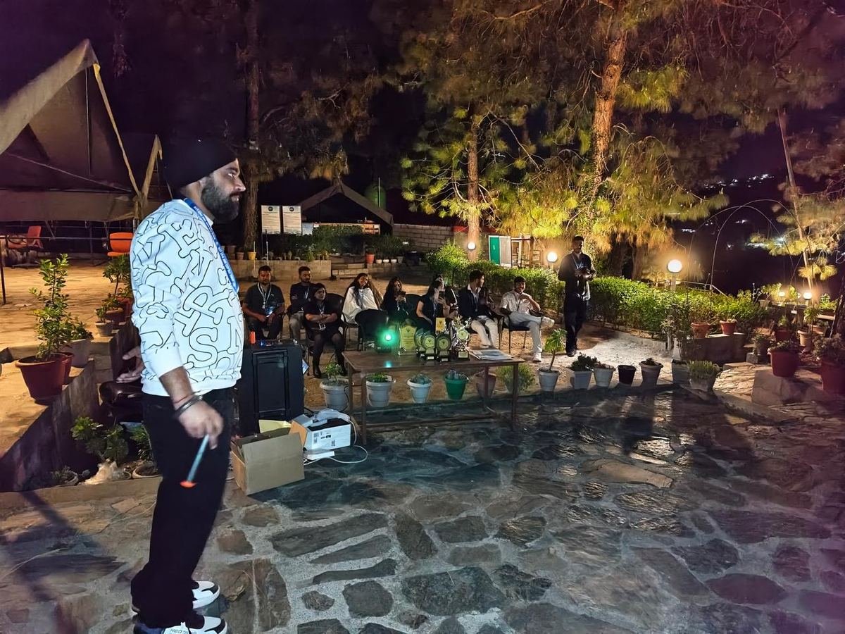 Corporate group seated outdoors at night under lit pine trees during an evening awards session