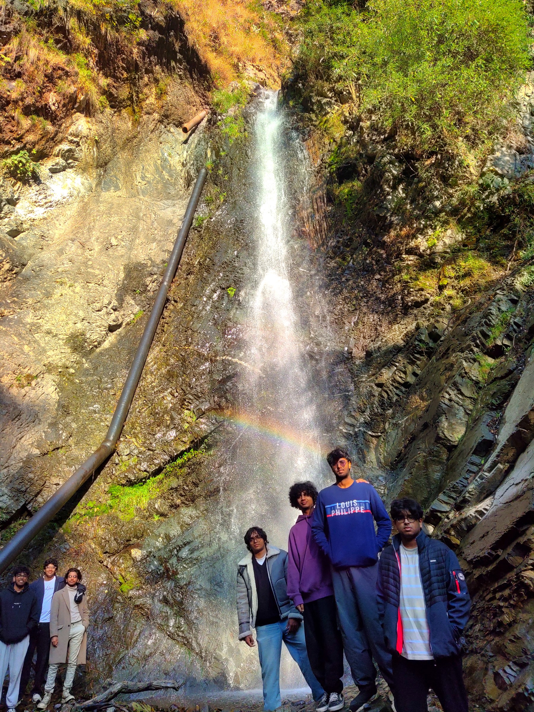 Group of young guests standing at a rainbow waterfall near The Glide Inn Shimla