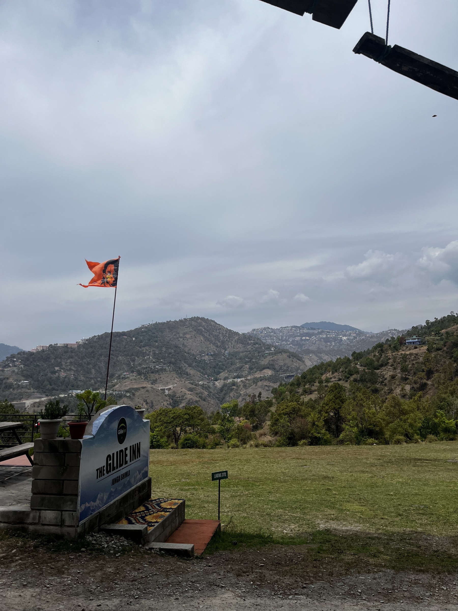 The Glide Inn entrance signboard with orange flag and Himalayan mountain panorama