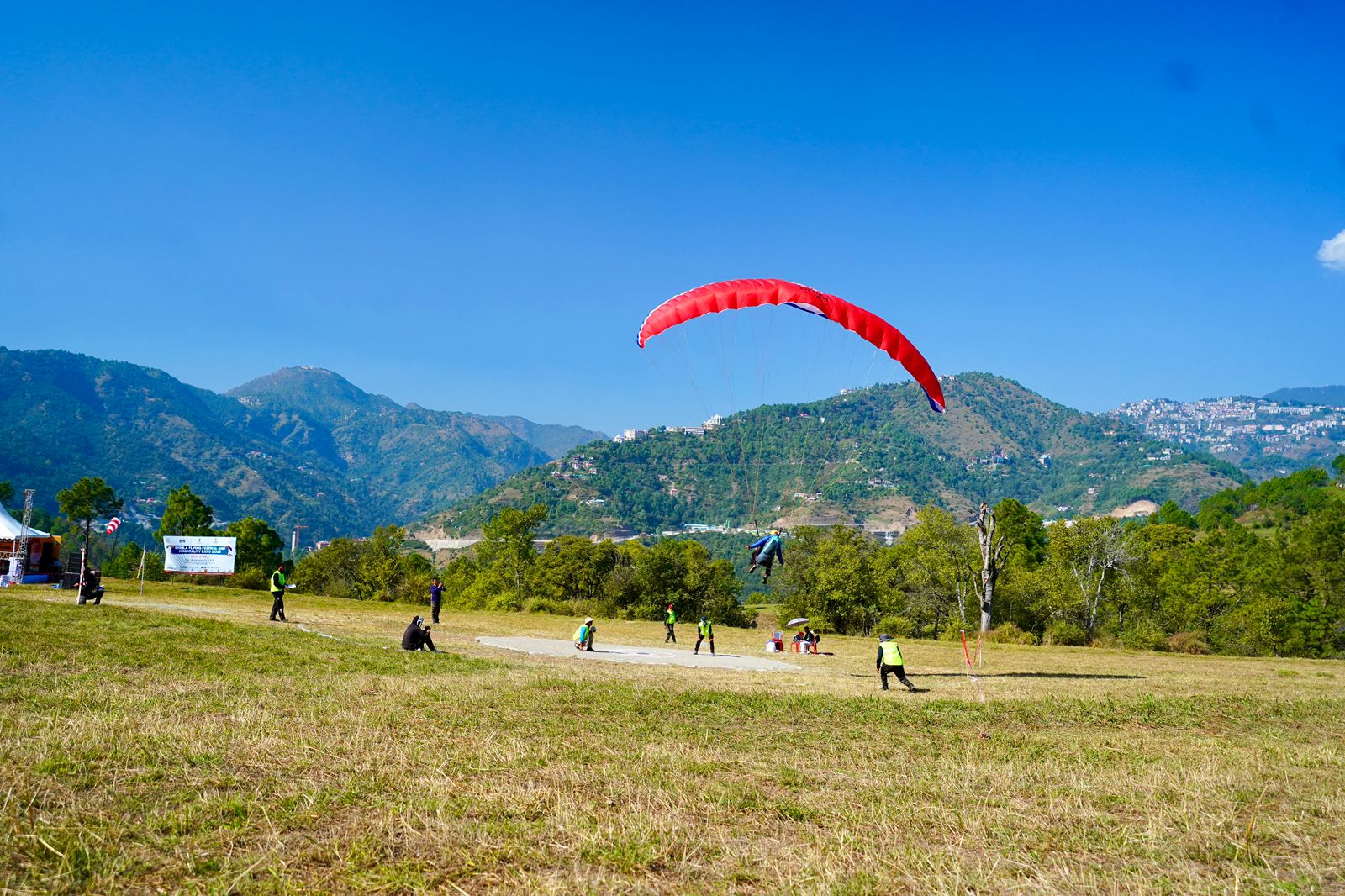 Tandem paraglider launching with red canopy over the Himalayan valley at The Glide Inn