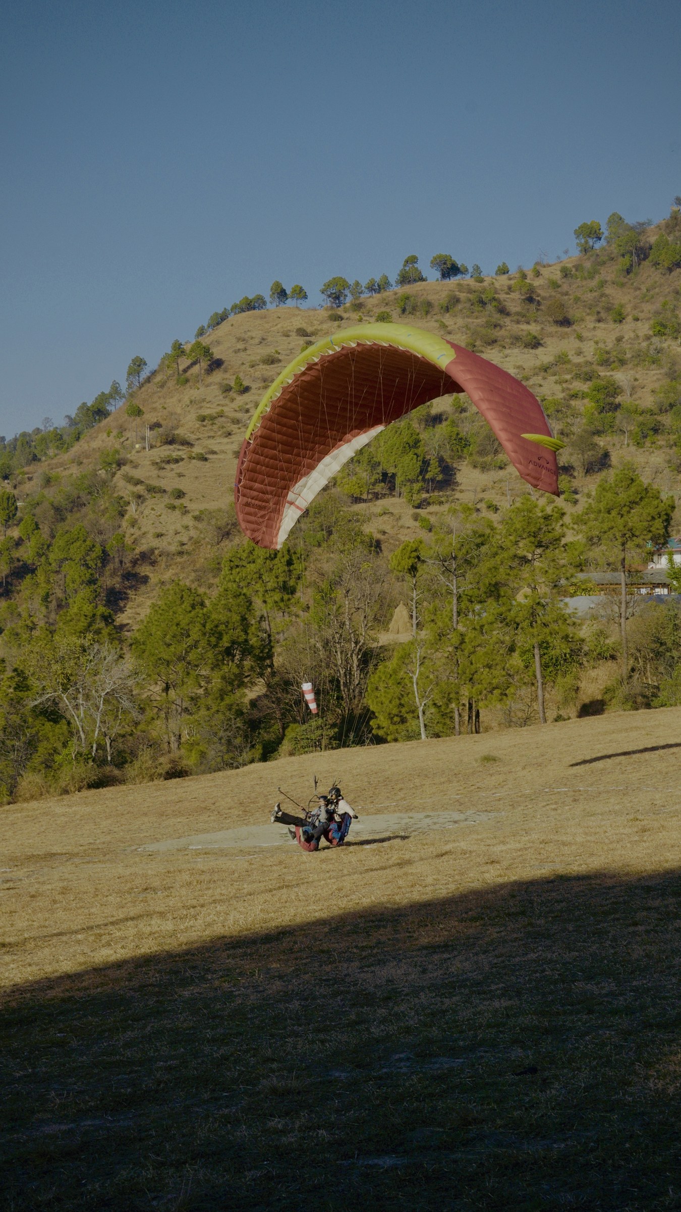Paraglider coming in to land on the open meadow at The Glide Inn Junga Shimla