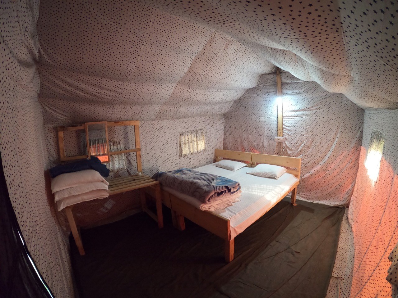 Cosy tent interior with two beds wooden furniture and warm fairy-light ceiling at The Glide Inn