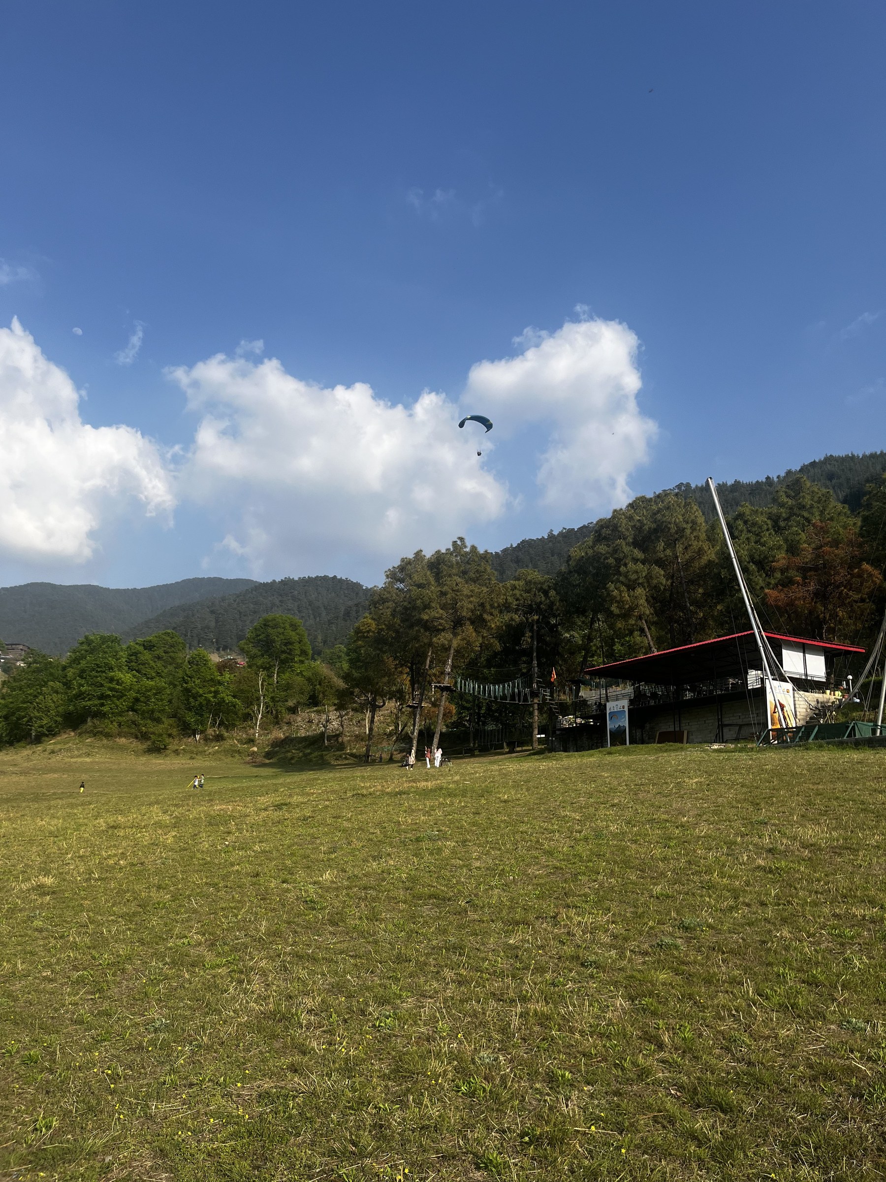 Open paragliding meadow with activity building and paraglider in the sky at The Glide Inn